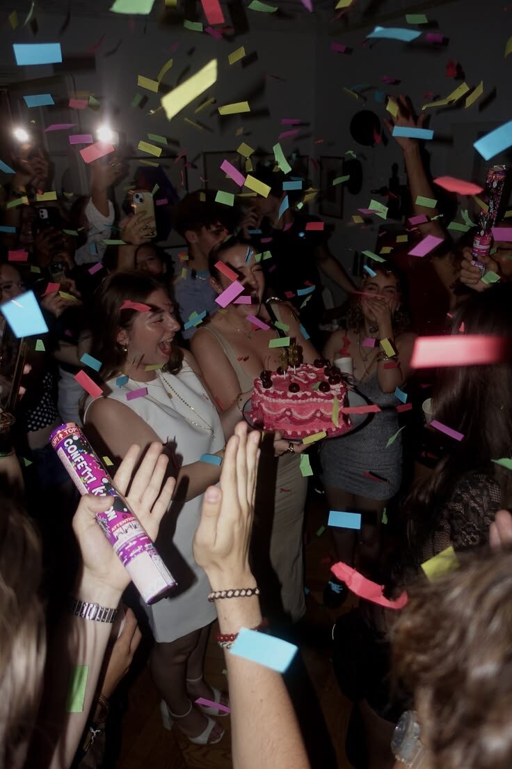 Friends under confetti with a birthday cake and sparklers